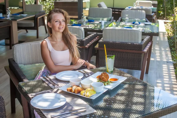 Fiatal nő ül a szabadtéri trópusi étterem élelmiszer — Stock Fotó