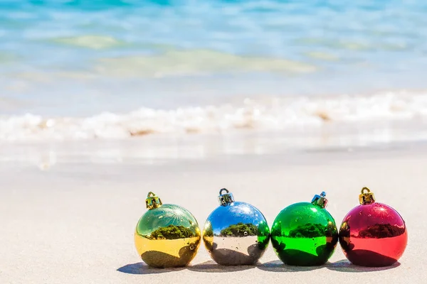 Vier Kerst Decoratie Veelkleurige Ballen Zeekust Met Wit Zand Blauwe — Stockfoto