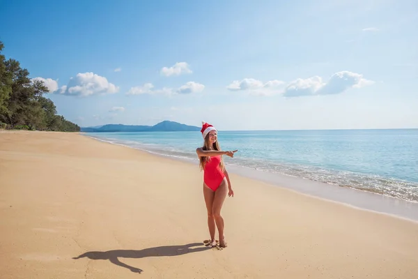 Молодая женщина в красном купальнике и шляпе Санта Клауса на пляже — стоковое фото