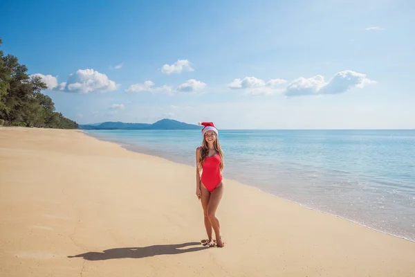 Молодая женщина в красном купальнике и шляпе Санта Клауса на пляже — стоковое фото