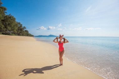 Genç kadın kırmızı mayo sahilde saçını tutan komik Noel geyik boynuzları giyiyor