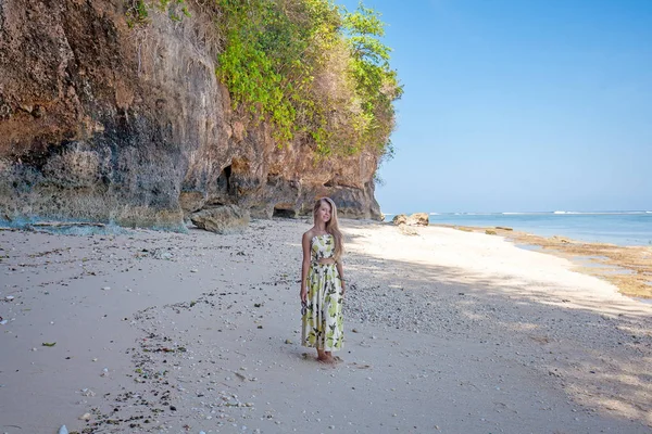 Mujer de pie en la playa cerca de las rocas y el mar — Foto de Stock