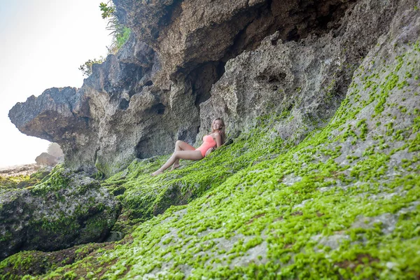 Kobieta w stroju kąpielowym, leżącego na skały porośnięte roślinnością — Zdjęcie stockowe