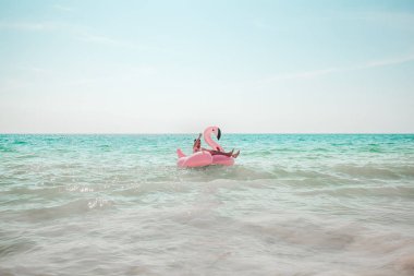 Adam pembe flamingo şişme havuz float eğleniyor