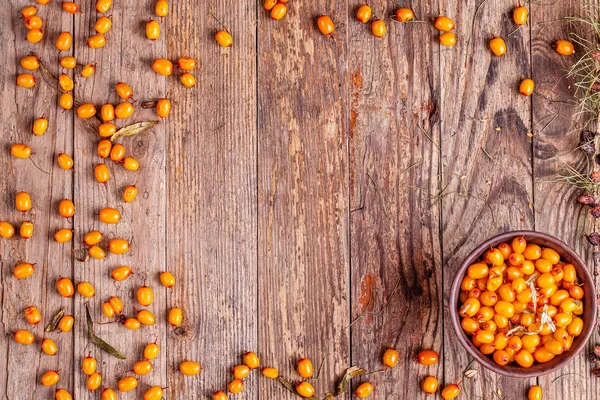 Frame from sea buckthorn with cup on wooden background — Stock Photo, Image