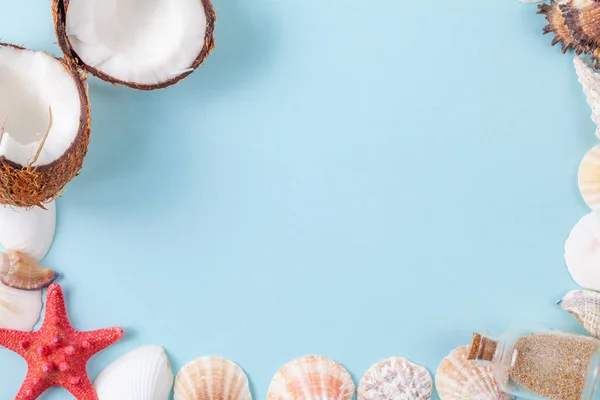 Flat lay composition with beautiful starfishes, sea shells, coconut and bottle with sand on a blue background — Stock Photo, Image