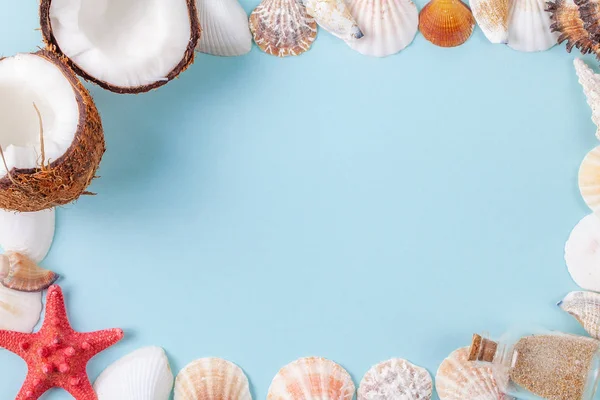 Platte lay frame samenstelling met prachtige starvissen, zeeschelpen, kokosnoot en fles met zand op een blauwe achtergrond — Stockfoto