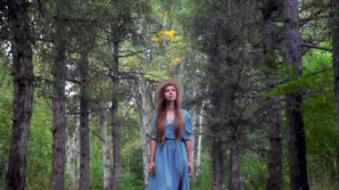 Bir çam ormanında bir patikada yürüyen genç güzel kadın