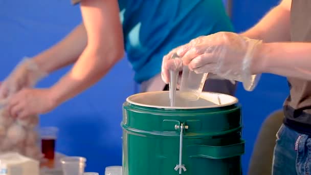 A man in gloves on a holiday pours tea into a plastic cup and gives it to child — Stock Video