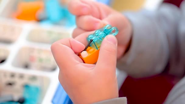 Mains d'enfants jouant avec une petite brique lego — Video