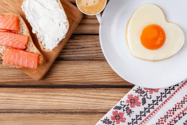 Breakfast: fried egg in the shape of a heart, sandwich and cup of espresso — Stock Photo, Image