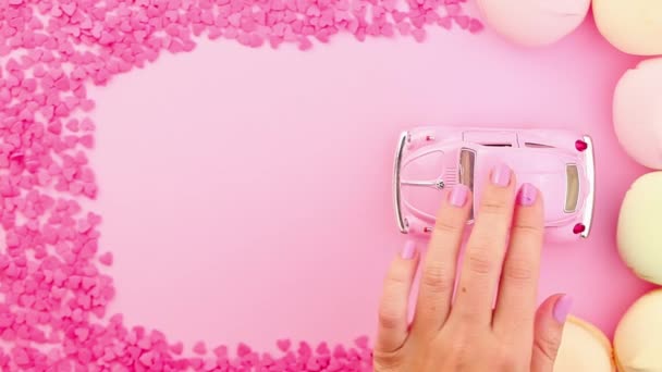 Ženská ruka tlačila růžovou retro hračku na růžovém pozadí