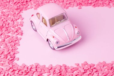 Kalpleri ve renkli marshmallow çerçeve ile pembe arka plan üzerinde Retro oyuncak araba