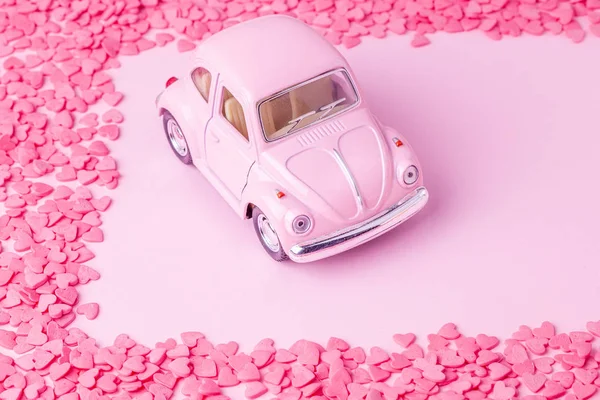 Retro speelgoed auto op roze achtergrond met frame van harten en gekleurde marshmallows — Stockfoto