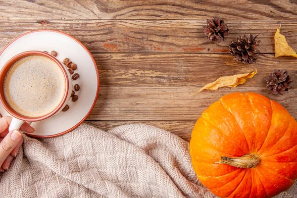 Hand holding cup of coffee on wooden background with pumpkin — Stock Photo, Image