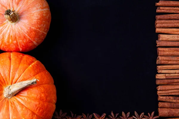 シナモンスティックとアニス星黒の背景とオレンジ色のカボチャのフレーム — ストック写真