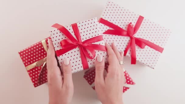 Las manos de la mujer sostiene y sacude las cajas de regalo de Navidad hechas a mano con cintas — Vídeos de Stock