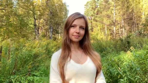 Zoom en el retrato de la joven hermosa chica en el bosque de otoño, mirando a la cámara — Vídeos de Stock