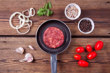 Sebze ile bir tavada taze sığır burger et: domates, soğan halkaları, sarımsak