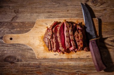 Eski bıçakla tahta kesme tahtasında biftek eti dilimleri. Üstte görüntü.