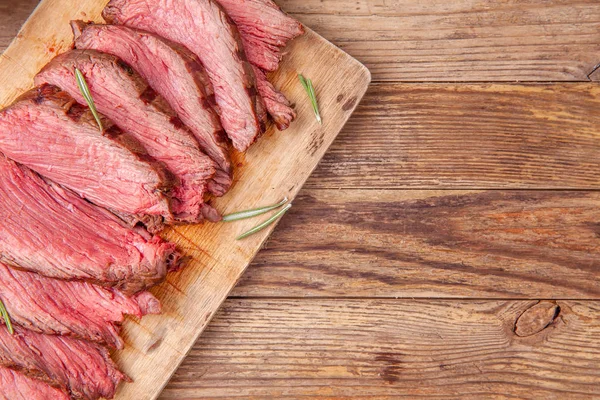 Kawałki średnio wysmażonego mięsa wołowego na drewnianej desce do krojenia. Przestrzeń kopiowania. — Zdjęcie stockowe