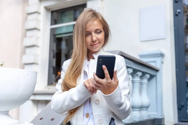 Joyeux jeune femme souriante à l'aide d'un smartphone extérieur sur l'échelle de style vintage — Photo