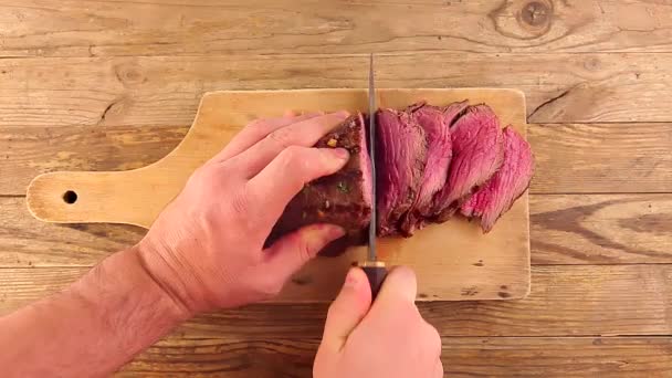 Uomo mano tagliando un arrosto di carne medio raro alla griglia da un coltello cacciatori — Video Stock