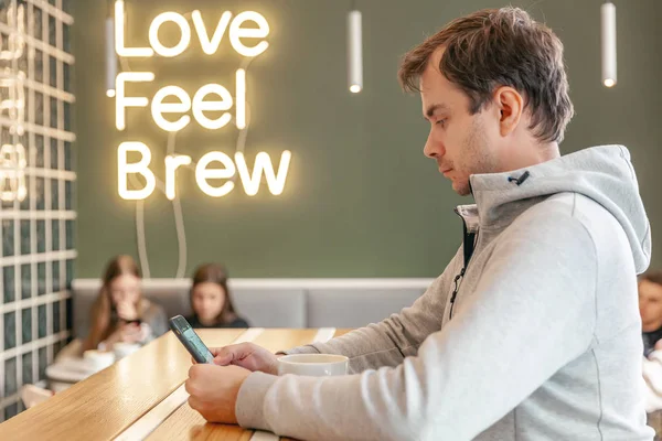 Retrato de un hombre serio y exitoso en la cafetería con café, usando un teléfono inteligente —  Fotos de Stock