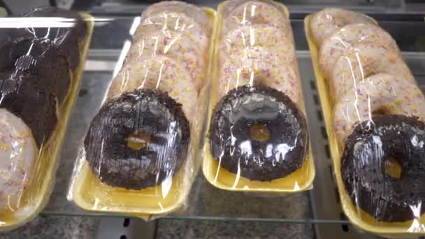 Esmalte de rosquillas heladas con chispas de colores en paquetes de plástico en el estante de la tienda — Vídeos de Stock