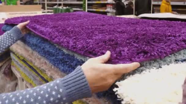 Manos de mujer eligiendo una alfombra textil en una ferretería en el centro comercial DIY — Vídeos de Stock