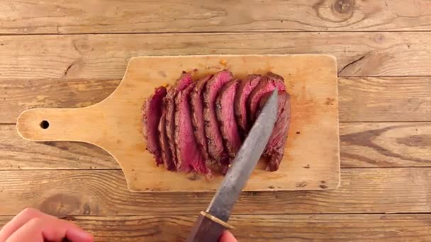 Man hand get hunters knife through sliced grilled medium rare roast beef — ストック動画