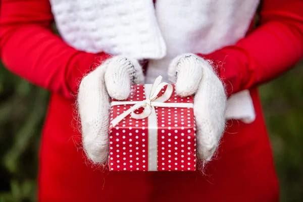Close-up van de handen in gebreide wanten met een handgemaakte kerst geschenkdoos — Stockfoto