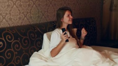 Üzgün, yorgun kadın TV 'de uzaktan kumandayla kanal değiştiriyor.