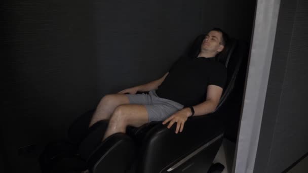 Чоловік лежить, розслабляється і насолоджується масажним кріслом в лаунж-зоні в аеропорту — стокове відео