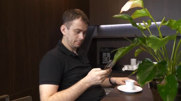 令人惊讶的男人与智能手机坐在咖啡店里，阅读好的互联网新闻 — 图库视频影像