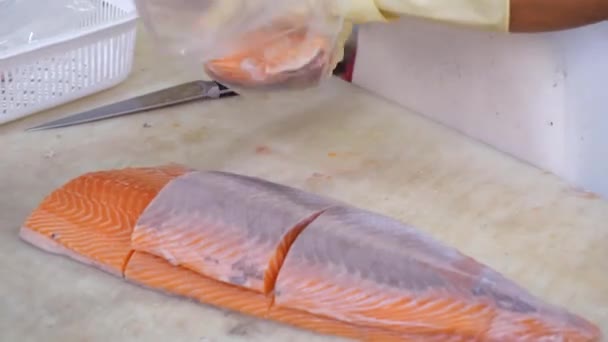 Lebensmittelgeschäft Arbeiter in Handschuhen packt frisches Lachsfilet in Plastiktüten — Stockvideo