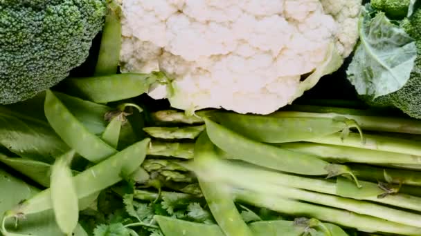 Movimento lento de ervilhas verdes caindo de cima em vegetais frescos — Vídeo de Stock