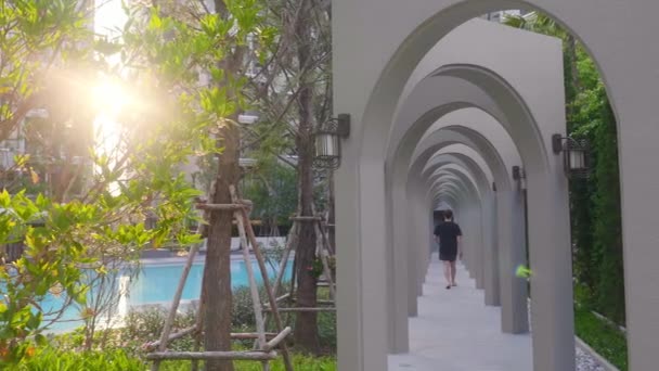 Homme marchant près de la belle piscine entourée d'arbres verts et de plantes — Video