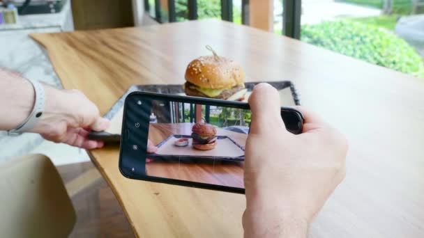 Uomo mani scattare foto sul telefono cellulare di hamburger con costoletta di manzo — Video Stock
