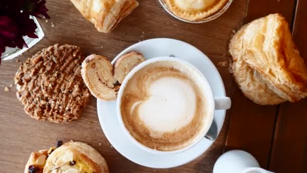 Frukost med croissanter, paj, kaka och kopp kaffe på träbord i Café — Stockvideo