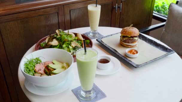 Délicieux déjeuner dans un café moderne avec salade fraîche, hamburger, frites et Poke Bowl — Video