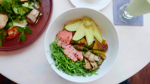 Insalata di salmone presa a mano con avocado, zucchine da tavola nel ristorante. Vista dall'alto — Video Stock