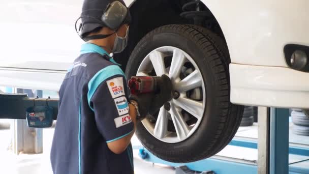 Mężczyzna zastępujący koło samochodu pneumatycznym kluczem udarowym w stacji obsługi naprawy — Wideo stockowe