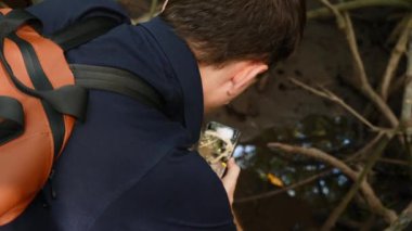 Genç Gezgin, Mangrove Trees Kökleri 'nin Akıllı Telefonu' nda Yakın plan Video Çekiyor