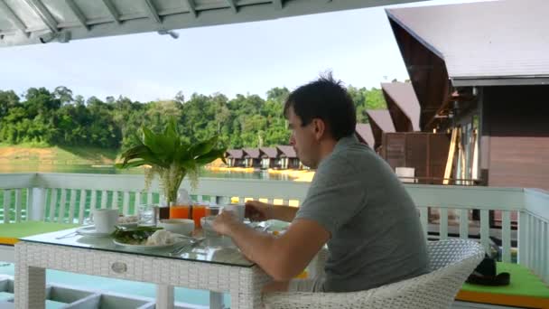 Man Take Breakfast in Nature at Outdoor Restaurant on Lake with floating Houses — Αρχείο Βίντεο