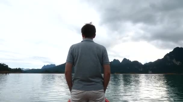 Человек стоит на лодке и наслаждается видом на Утреннее озеро — стоковое видео