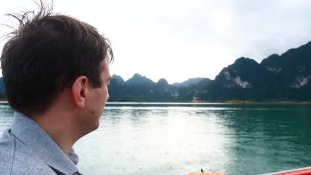 Moción lenta del hombre en barco en el lago de la mañana con montañas y señalando un dedo — Vídeos de Stock