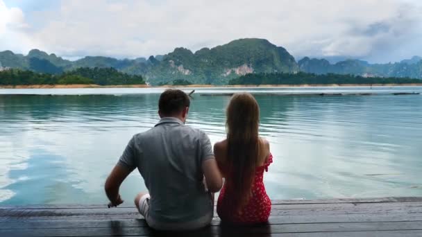 男は湖と美しい山の風景の日に女性から離れて移動 — ストック動画