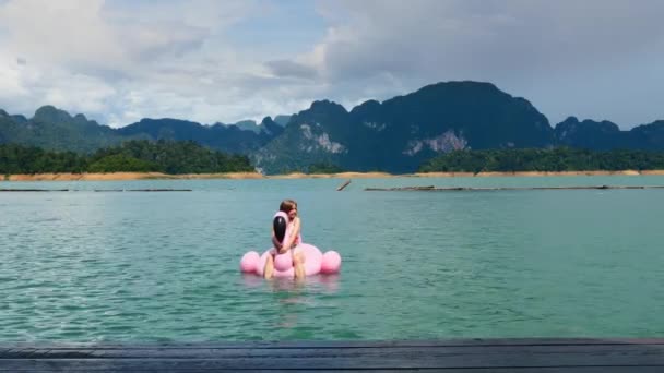 Mujer de vacaciones Relájese en el flamenco inflable rosa en el lago azul con la montaña — Vídeos de Stock
