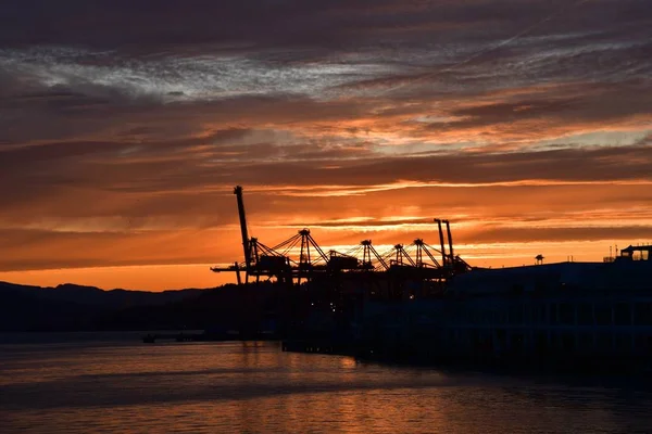 A picture of the silhouette of Metro Vancouver\'s port against the sunrise.Vancouver BC Canada
